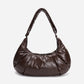 A dark brown shiny Croissant-shaped shoulder bag in polish brown color by Dude & Bestie