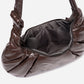 A dark brown shiny Croissant-shaped shoulder bag in polish brown color by Dude & Bestie